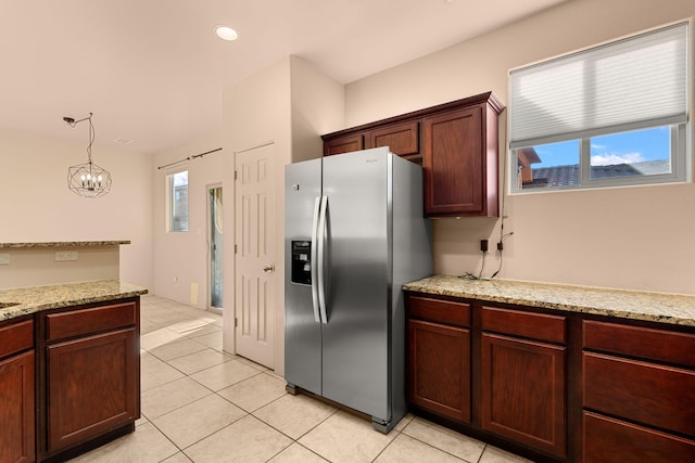 kitchen featuring light stone counters, stainless steel fridge with ice dispenser, plenty of natural light, and hanging light fixtures