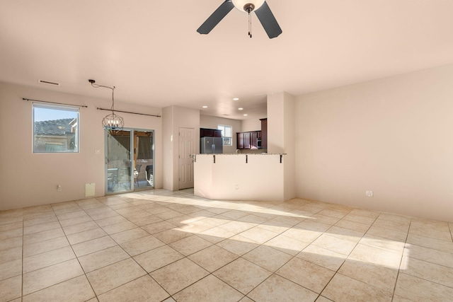 unfurnished living room with light tile patterned floors and ceiling fan with notable chandelier