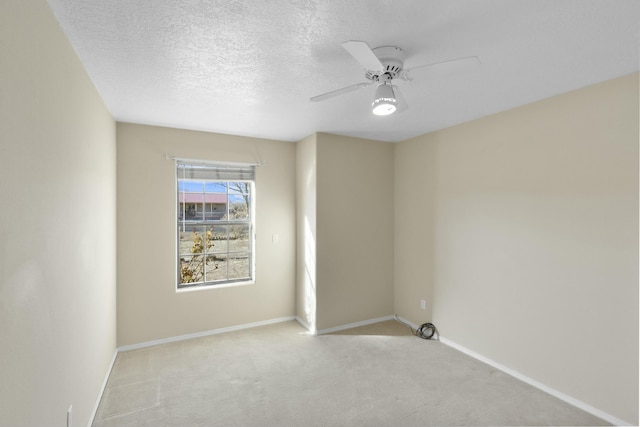 spare room featuring light carpet, ceiling fan, and a textured ceiling