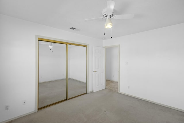 unfurnished bedroom with light colored carpet, ceiling fan, and a closet