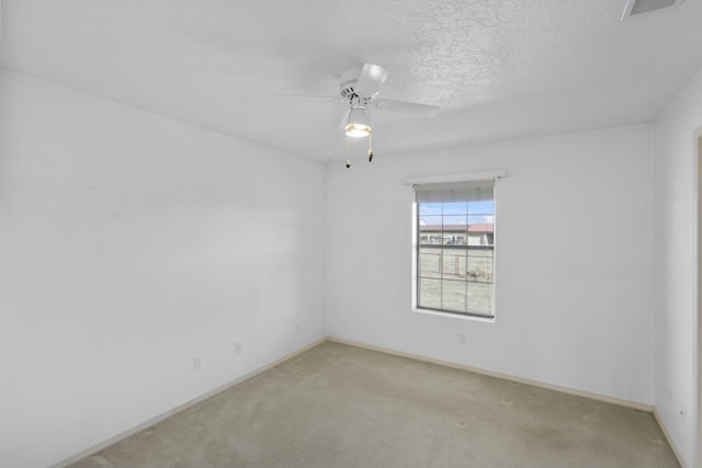 spare room with ceiling fan, light colored carpet, and a textured ceiling