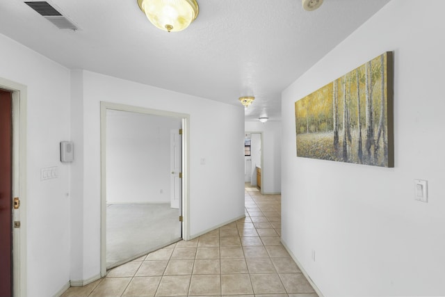 hall with a textured ceiling and light tile patterned floors