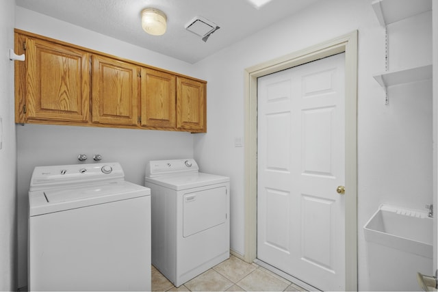 laundry area with light tile patterned floors, washer and clothes dryer, and cabinets