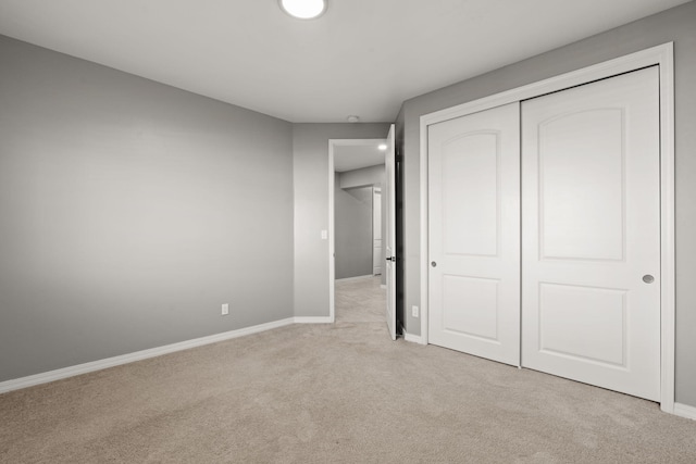 unfurnished bedroom with light colored carpet and a closet