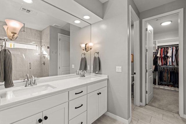 bathroom with a shower with door, vanity, and tile patterned floors