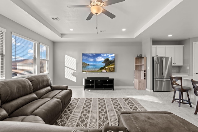 living room with ceiling fan and a tray ceiling