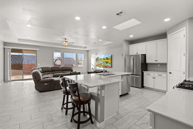 kitchen with an island with sink, appliances with stainless steel finishes, sink, and white cabinets