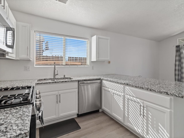 kitchen featuring sink, light hardwood / wood-style flooring, white cabinetry, stainless steel appliances, and light stone countertops