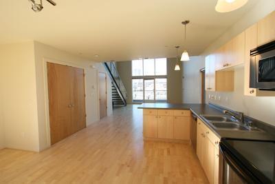 kitchen featuring light brown cabinetry, sink, decorative light fixtures, light hardwood / wood-style flooring, and kitchen peninsula