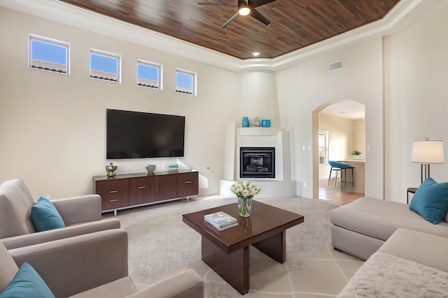 living room featuring ceiling fan, a large fireplace, a wealth of natural light, and wooden ceiling