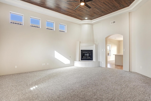 unfurnished living room featuring wood ceiling, light colored carpet, a large fireplace, and ceiling fan