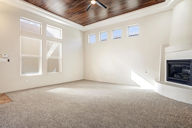 unfurnished living room with a fireplace, a high ceiling, carpet, and wooden ceiling