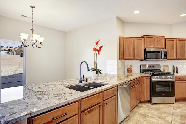 kitchen with sink, appliances with stainless steel finishes, backsplash, hanging light fixtures, and light stone counters