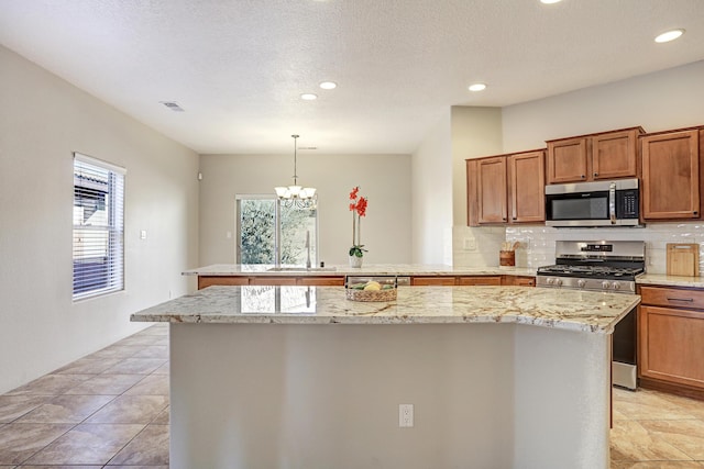 kitchen with stainless steel appliances, a healthy amount of sunlight, a center island, and decorative light fixtures