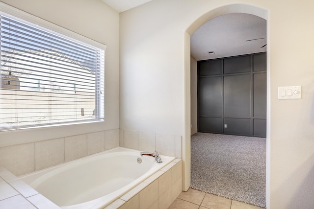 bathroom with tile patterned flooring, a healthy amount of sunlight, and tiled bath