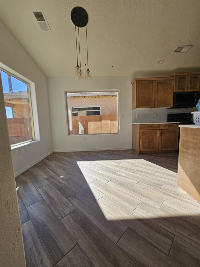 kitchen with decorative light fixtures, vaulted ceiling, and a textured ceiling