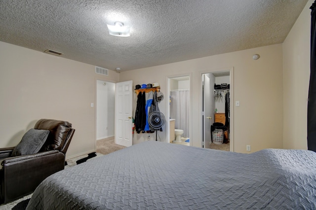 carpeted bedroom with a walk in closet, connected bathroom, a closet, and a textured ceiling