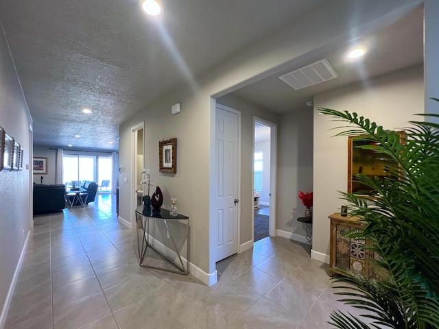 hallway featuring light tile patterned floors and a textured ceiling