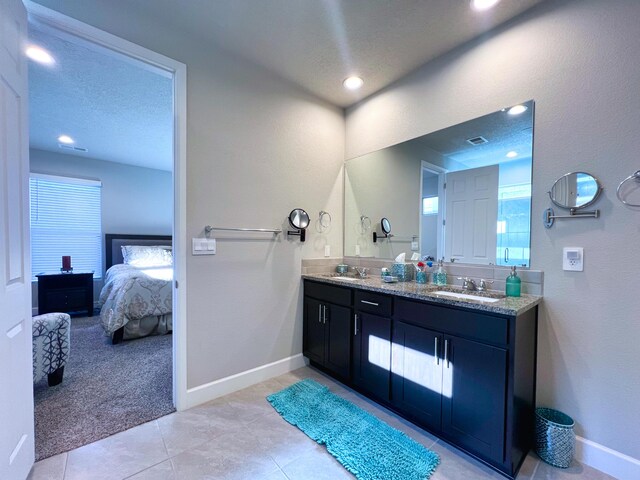 bathroom with tile patterned flooring, vanity, and a textured ceiling