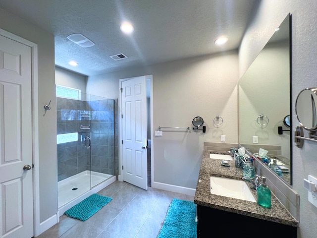 bathroom with an enclosed shower, vanity, tile patterned flooring, and a textured ceiling