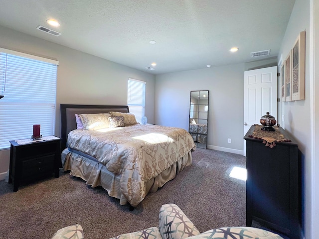 bedroom featuring a textured ceiling and dark colored carpet