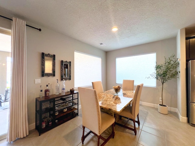 tiled dining space featuring a healthy amount of sunlight and a textured ceiling