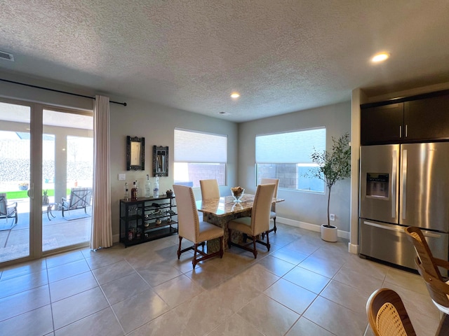 dining area featuring light tile patterned floors and a textured ceiling