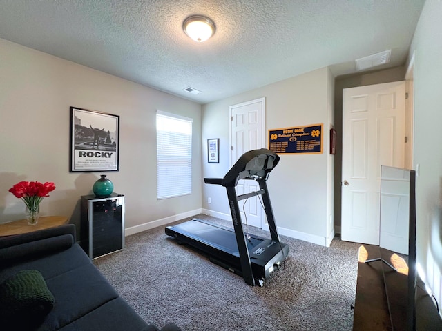 exercise room featuring beverage cooler, a textured ceiling, and carpet flooring