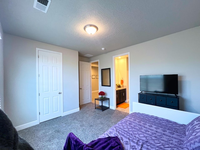 carpeted bedroom with connected bathroom and a textured ceiling