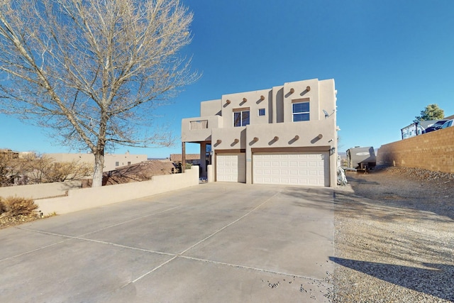 view of front facade featuring concrete driveway, fence, and stucco siding