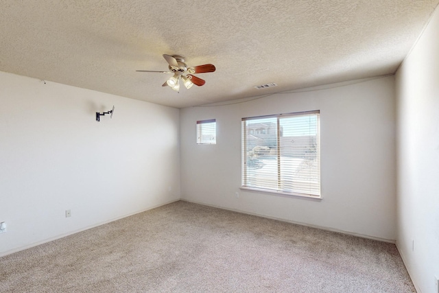 carpeted empty room featuring a textured ceiling, visible vents, and a ceiling fan