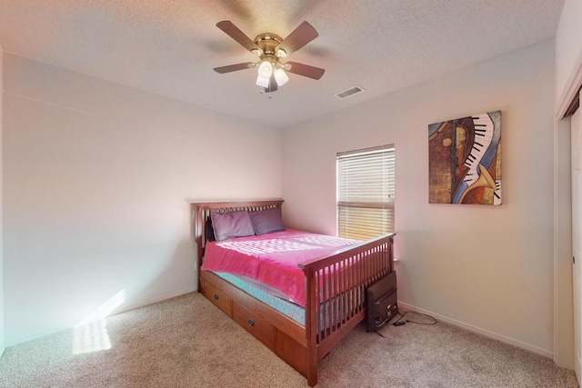 bedroom featuring visible vents, a textured ceiling, and light colored carpet