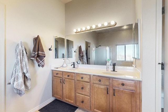 full bathroom with double vanity, a stall shower, and a sink