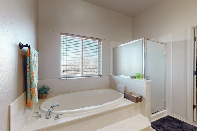 bathroom with a stall shower and a garden tub