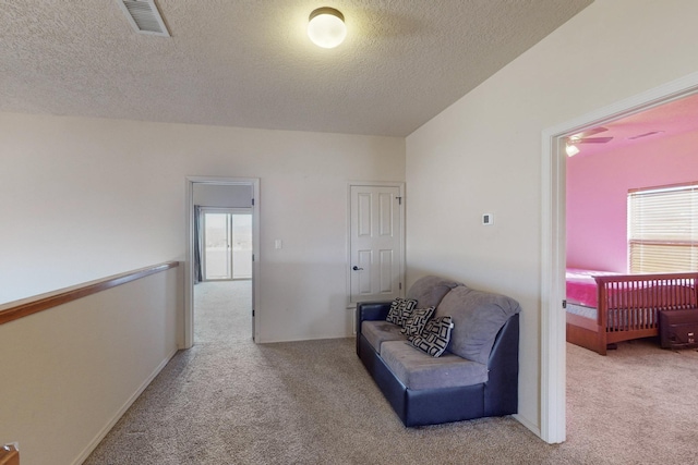 sitting room with light carpet, a textured ceiling, and visible vents