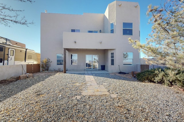 rear view of property featuring stucco siding, fence, and a patio