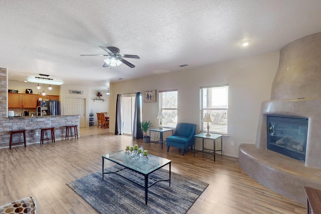 living area featuring a textured ceiling, light wood finished floors, a fireplace, and visible vents