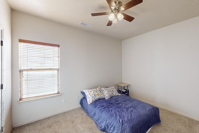 bedroom with light colored carpet, visible vents, a ceiling fan, a textured ceiling, and baseboards