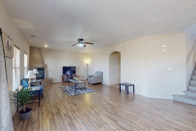 living area featuring arched walkways, visible vents, stairway, a textured ceiling, and wood finished floors