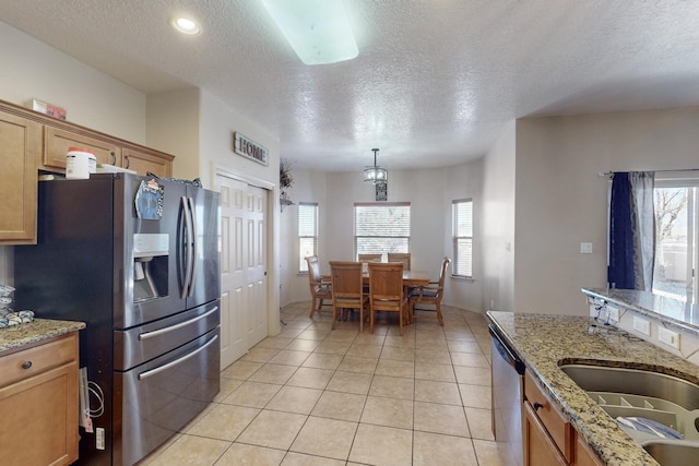 kitchen with stainless steel appliances, a wealth of natural light, and light stone counters