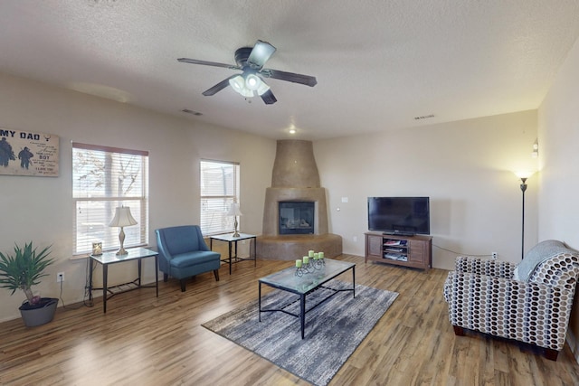 living room featuring a textured ceiling, wood finished floors, visible vents, and a ceiling fan