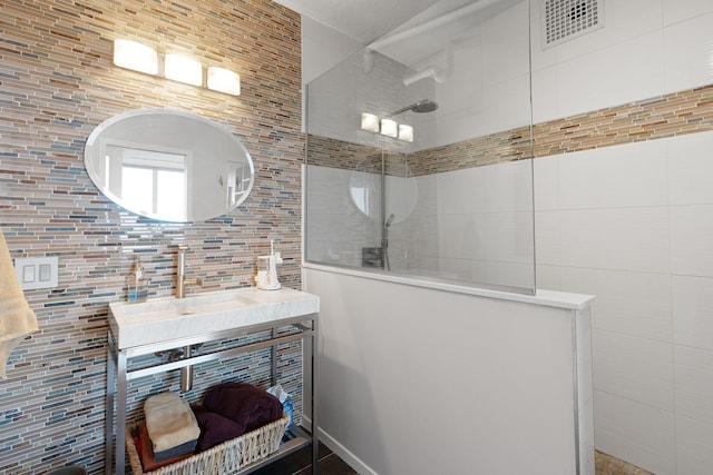 bathroom featuring tile walls, sink, decorative backsplash, and a shower