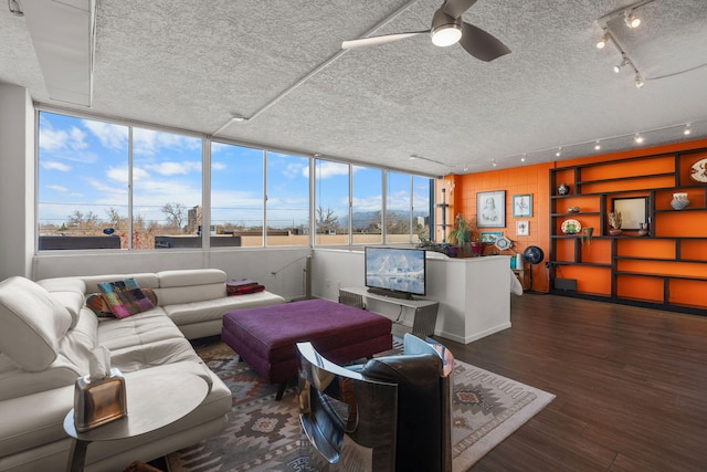 living room with dark wood-type flooring, ceiling fan, and a textured ceiling