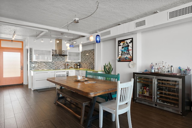 dining room with wine cooler, track lighting, dark hardwood / wood-style flooring, and a textured ceiling