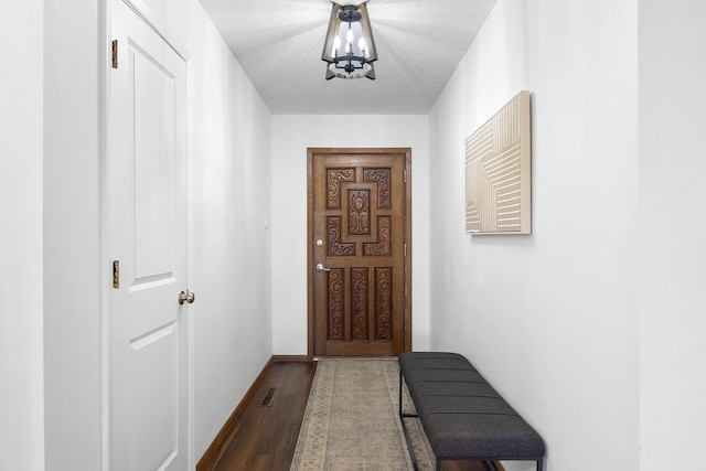 hallway featuring dark hardwood / wood-style floors, a chandelier, and a textured ceiling