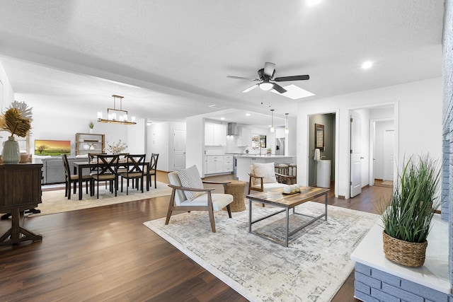 living room featuring dark hardwood / wood-style floors, ceiling fan with notable chandelier, and a textured ceiling