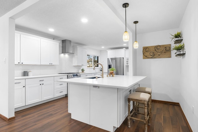 kitchen with white cabinets, stainless steel appliances, an island with sink, and wall chimney exhaust hood