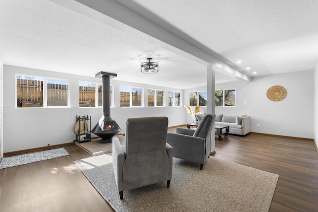 dining room featuring dark wood-type flooring, lofted ceiling with beams, a textured ceiling, and a wood stove