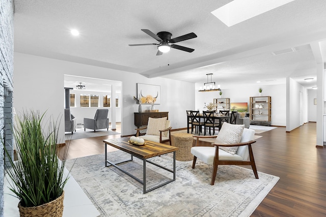 living room with beamed ceiling, ceiling fan, dark hardwood / wood-style floors, and a textured ceiling