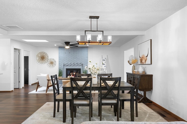 dining space with dark hardwood / wood-style flooring, a brick fireplace, and a textured ceiling